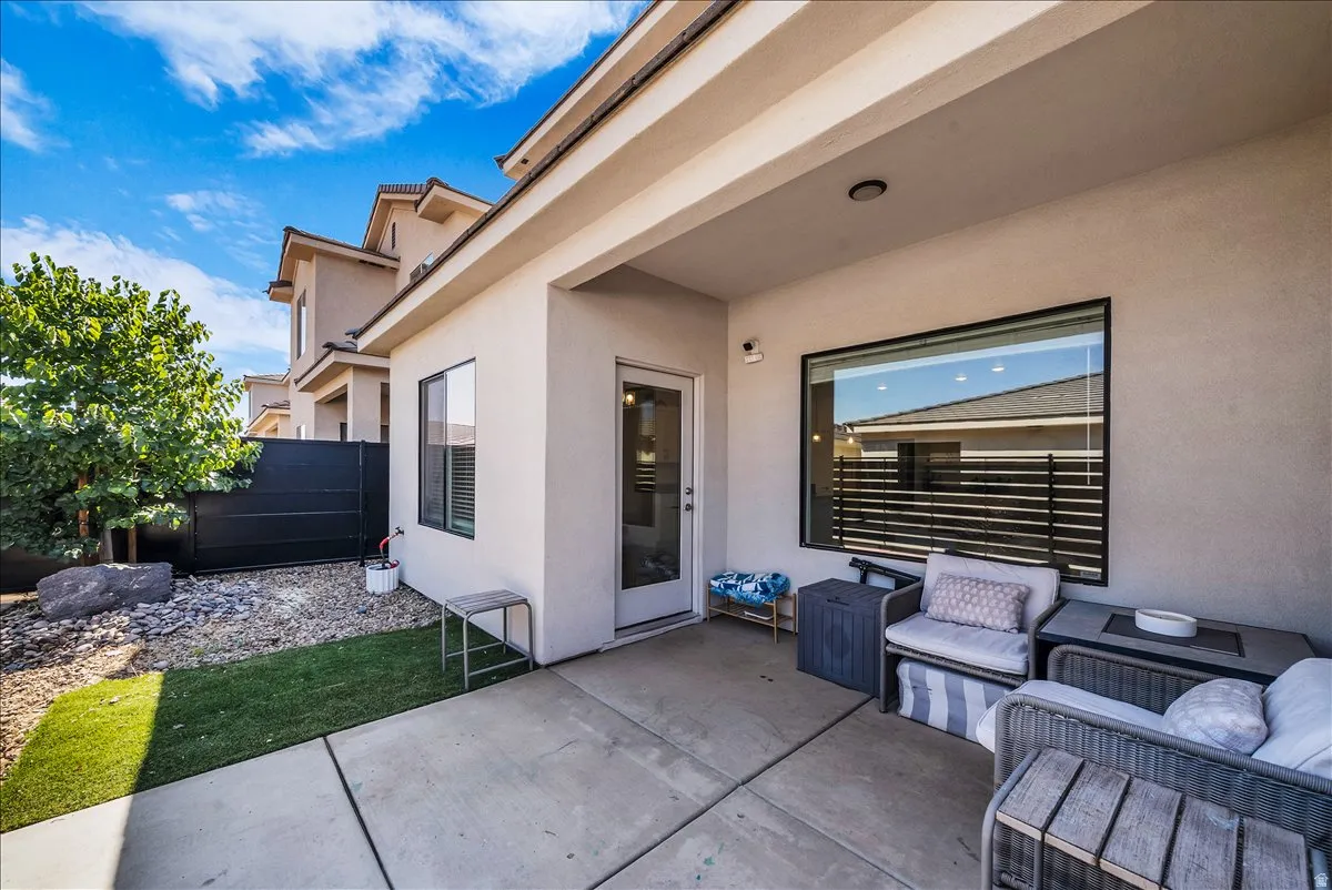 Covered outdoor patio with concrete flooring, stucco exterior, and a large fixed-pane window