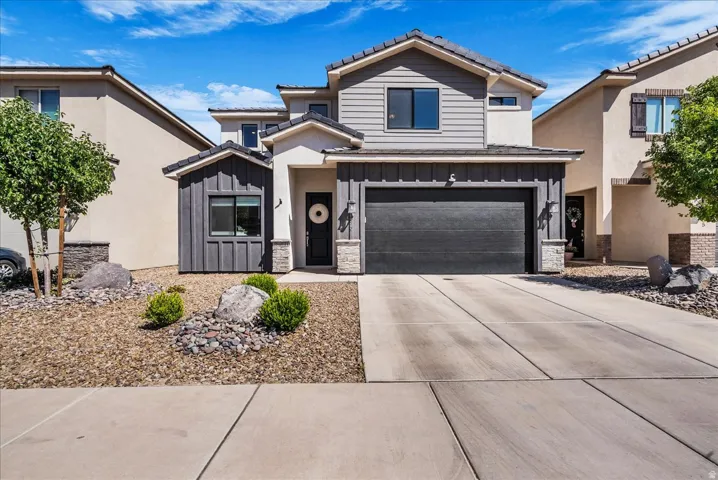 Contemporary two-story residence featuring a dark gray garage door and a contrasting light stucco and dark siding facade
