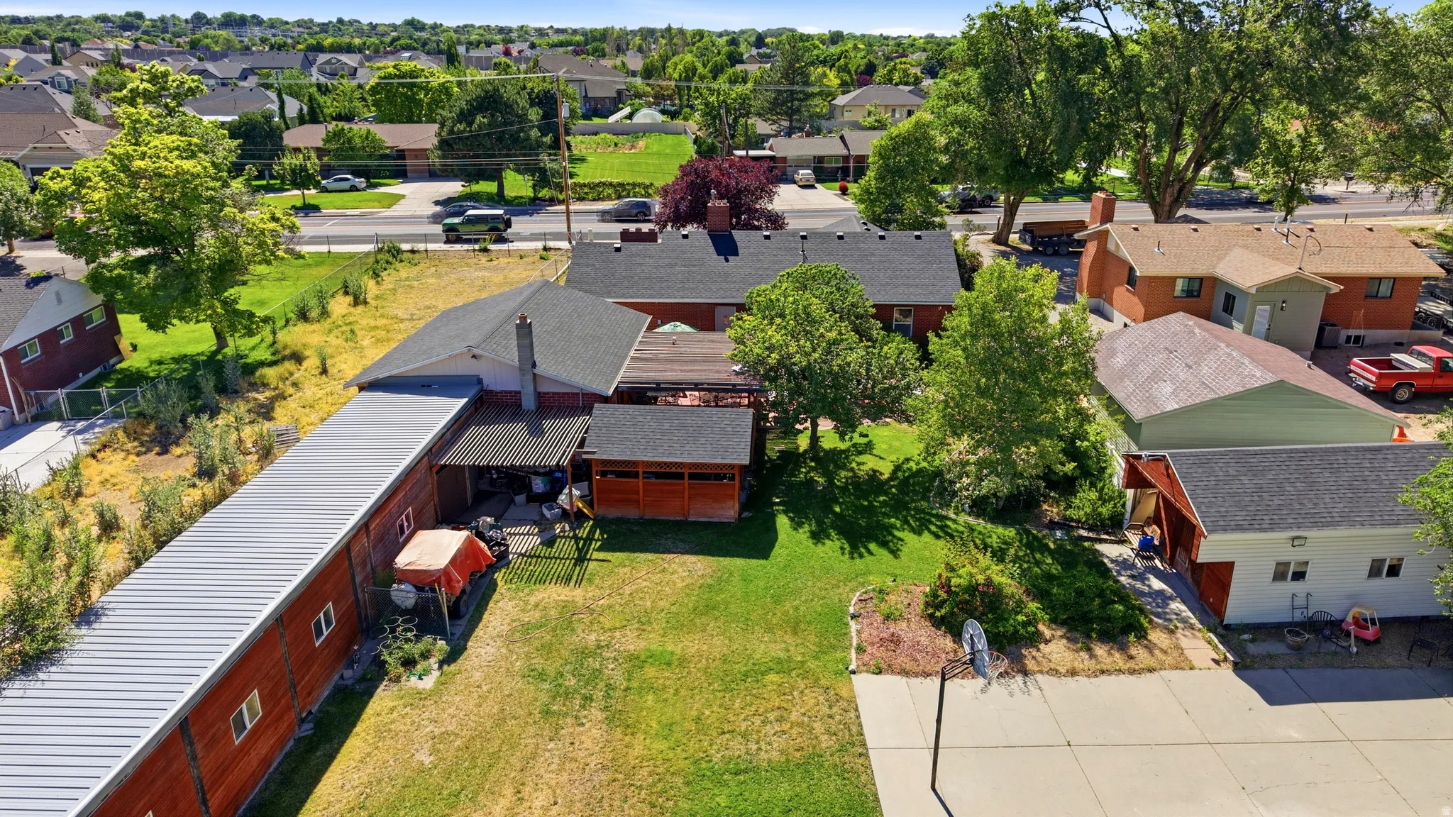 Expansive property featuring a large detached outbuilding with a metal roof, a covered patio area, and mature trees providing shade