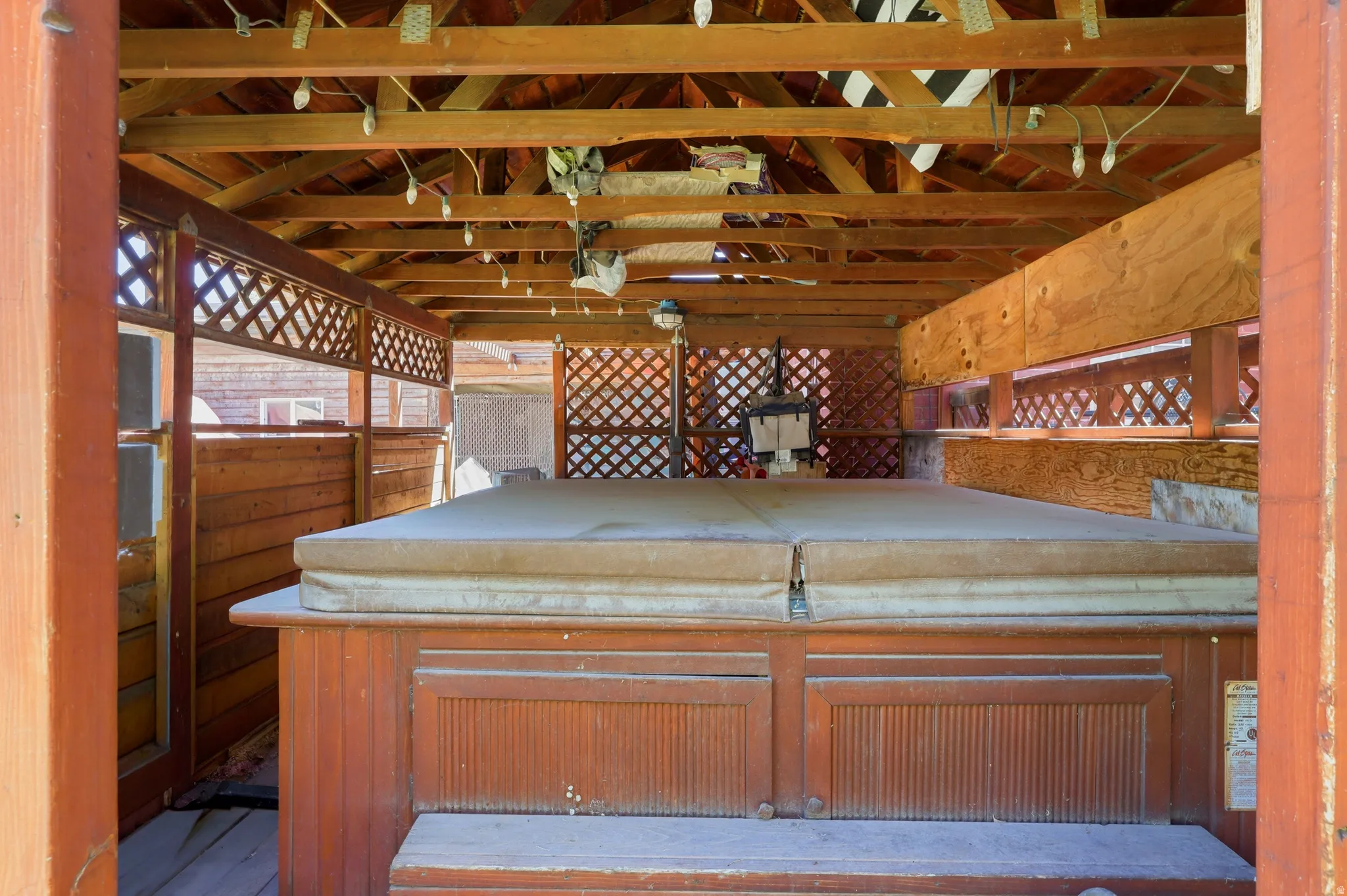 Covered spa area featuring a wood-finish enclosure and overhead trellis structure