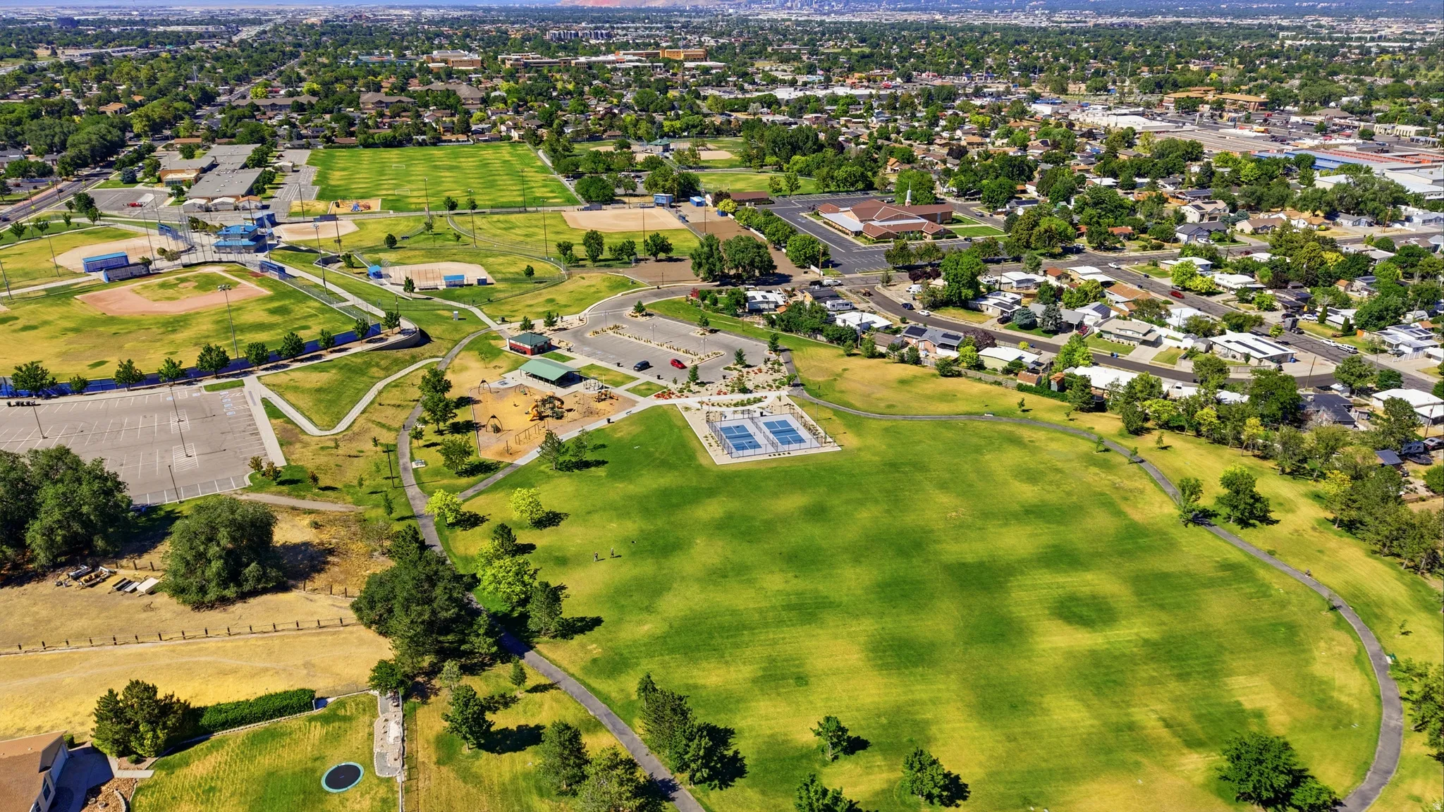 Expansive green spaces featuring walking paths, multiple sports fields, tennis courts, and a playground