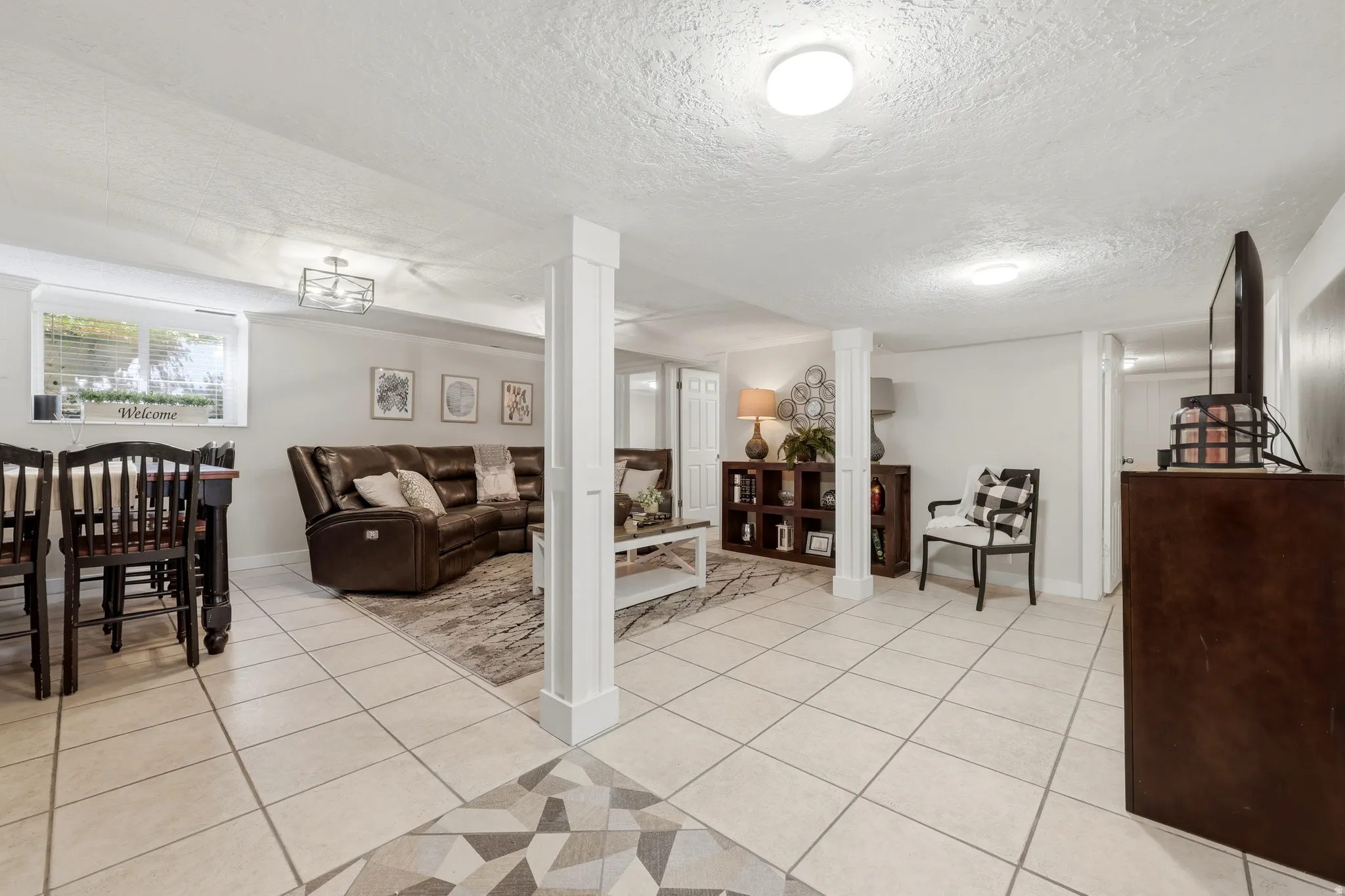 Spacious lower-level area featuring light-toned tile flooring, recessed lighting, and a window with blinds