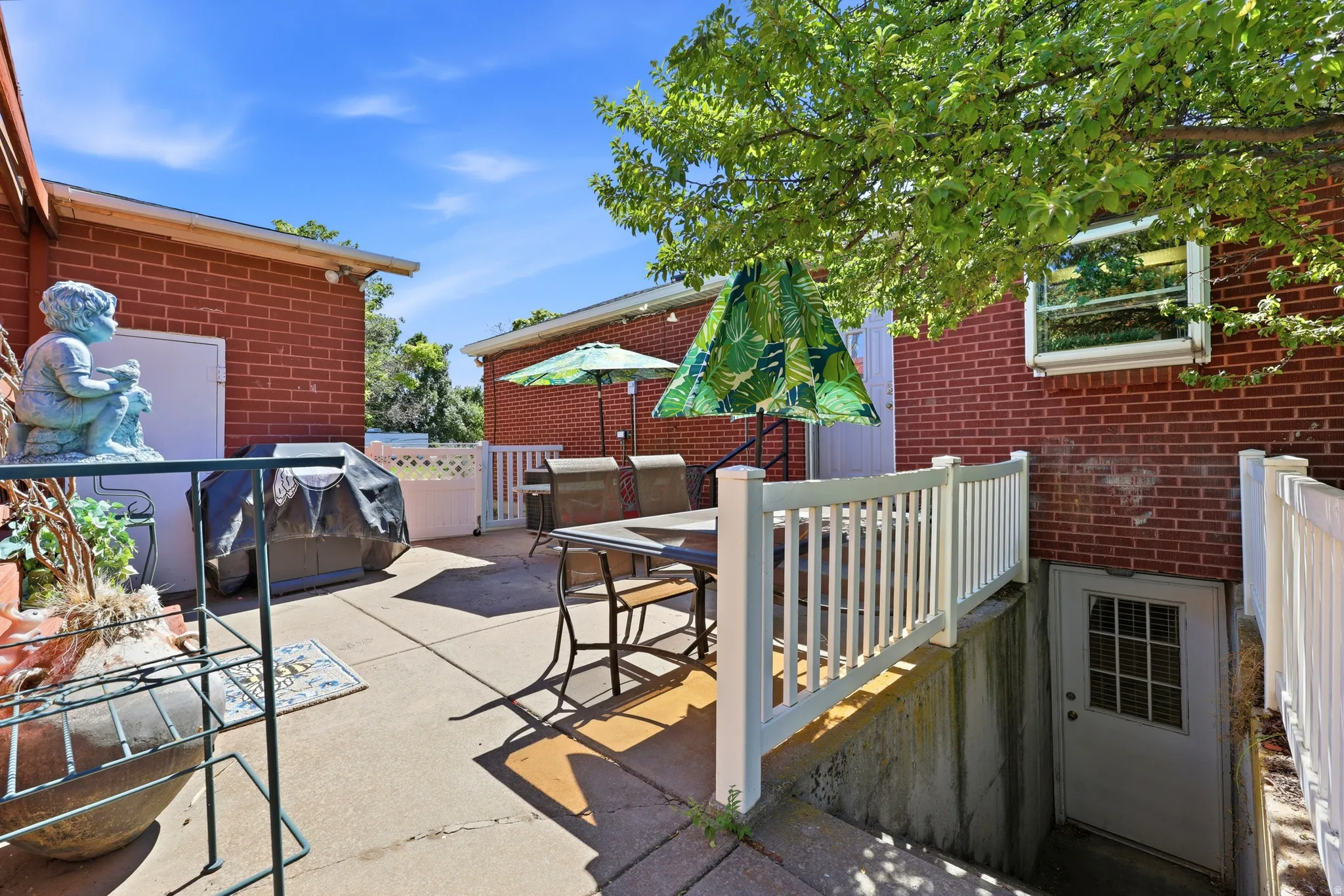 Expansive concrete patio area with brick exterior walls and white fencing