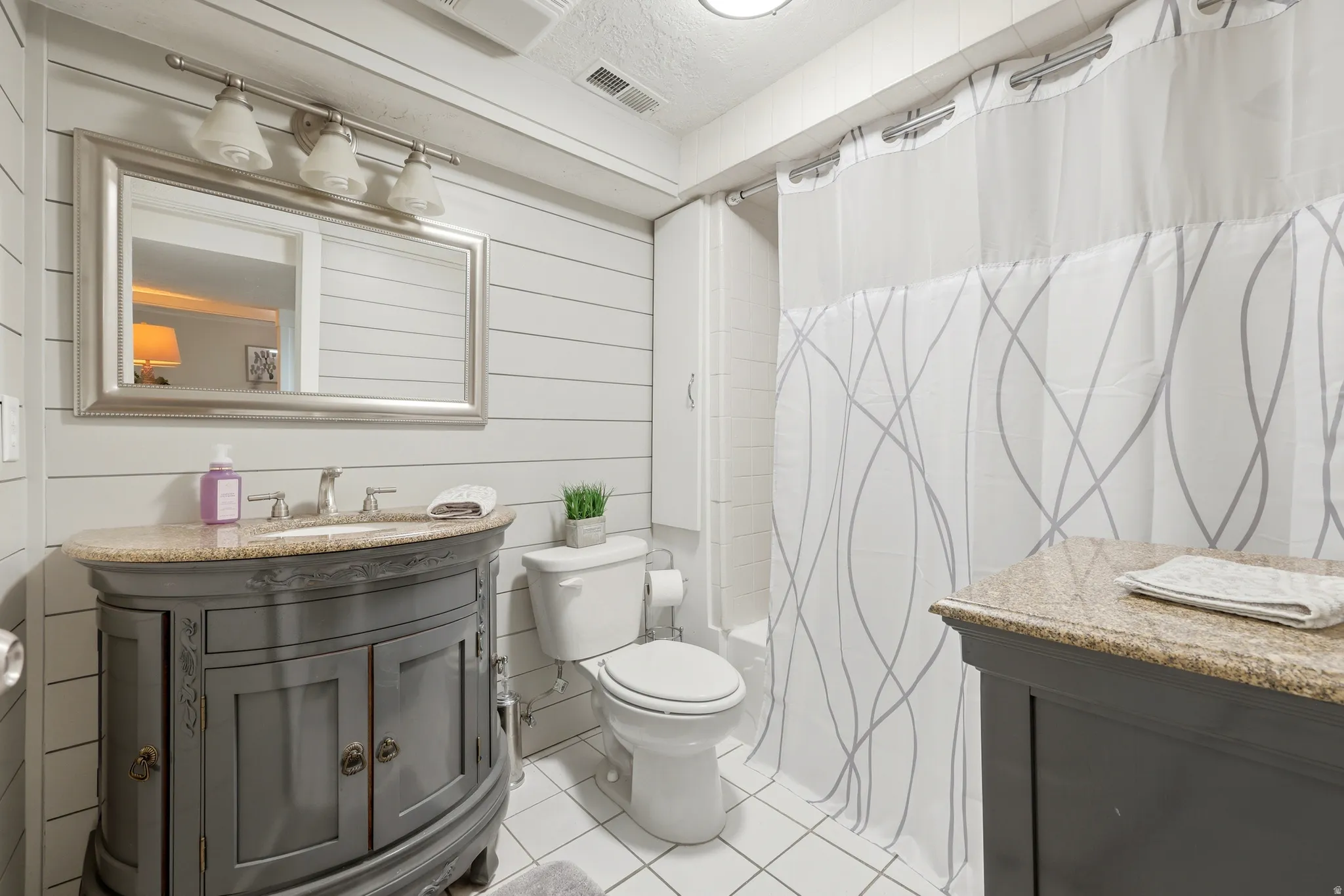 Bathroom featuring a gray vanity with an undermount sink, granite countertop, and brushed nickel faucet