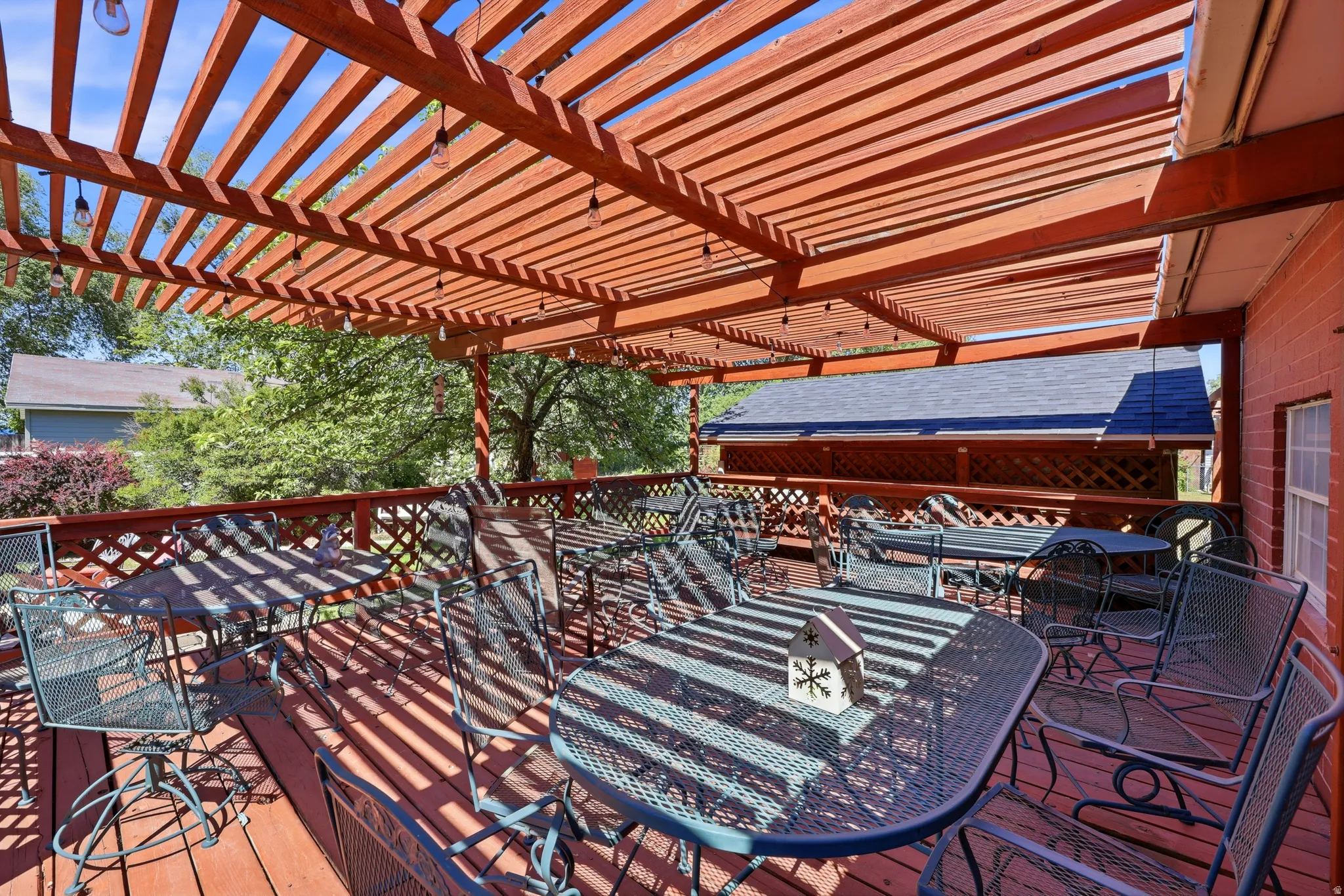Expansive outdoor deck featuring a full-coverage pergola, wood-finish flooring, lattice railing, and brick exterior