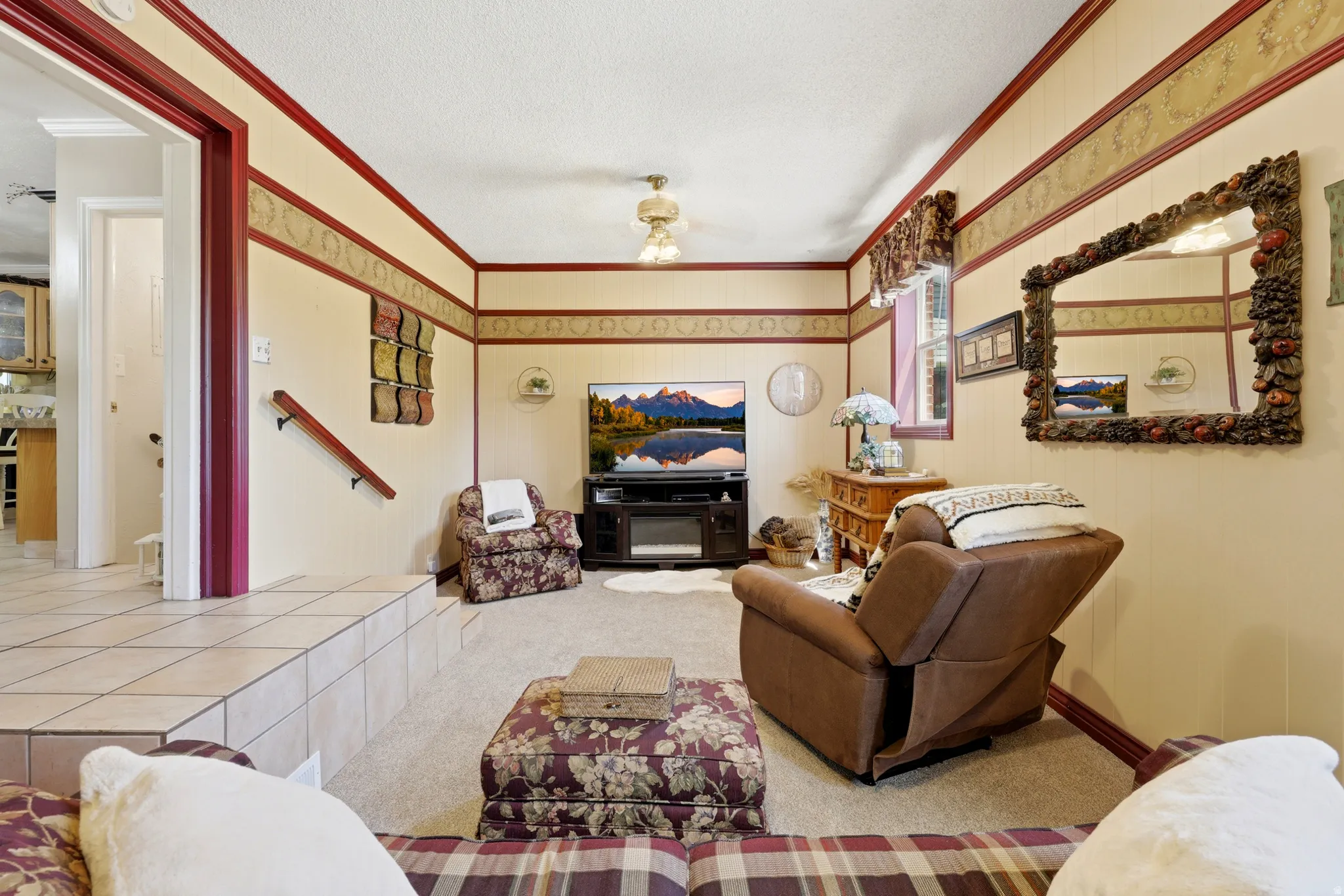 Carpeted living area featuring a built-in entertainment console with an electric fireplace, a decorative wall mirror, and a window with valance