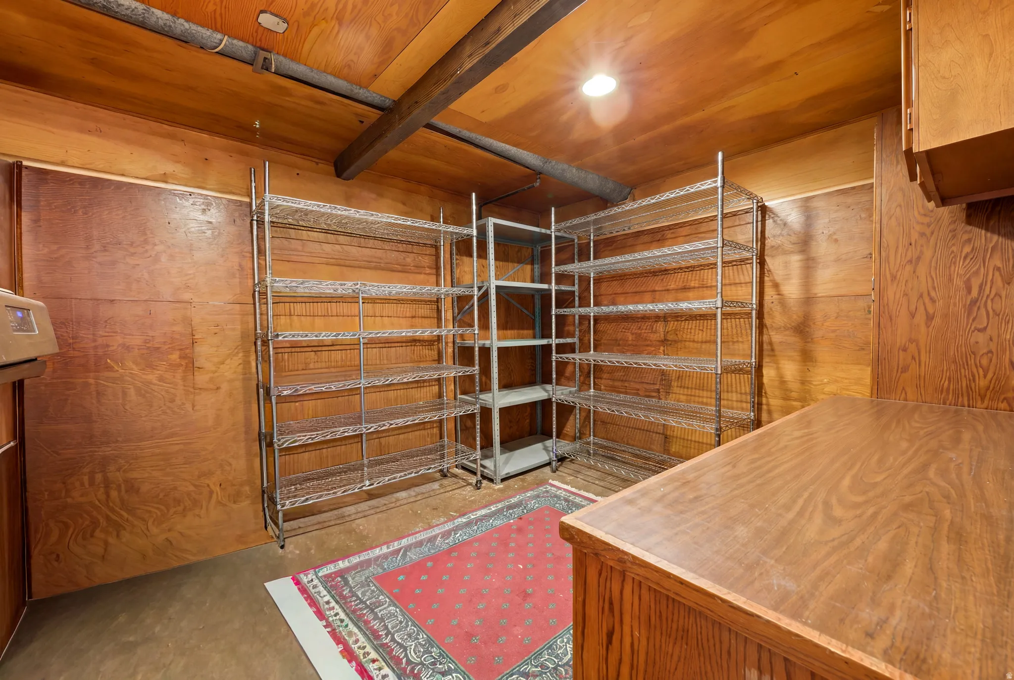 Utility room featuring wood-paneled walls, wood-finish ceiling, and exposed wood beams