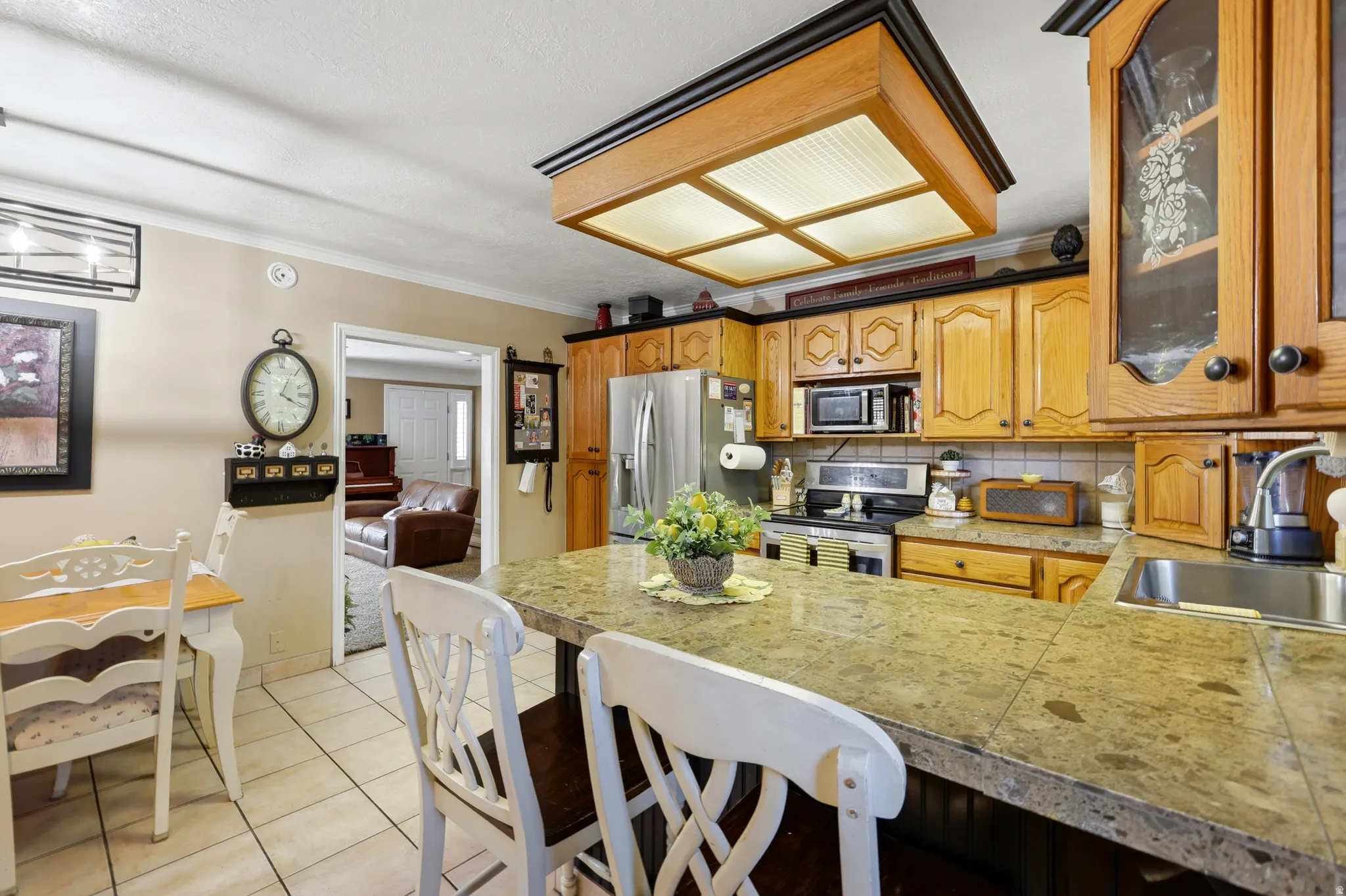 Kitchen featuring wood cabinetry, stone countertops, stainless steel appliances, tile flooring, and a central island with bar seating