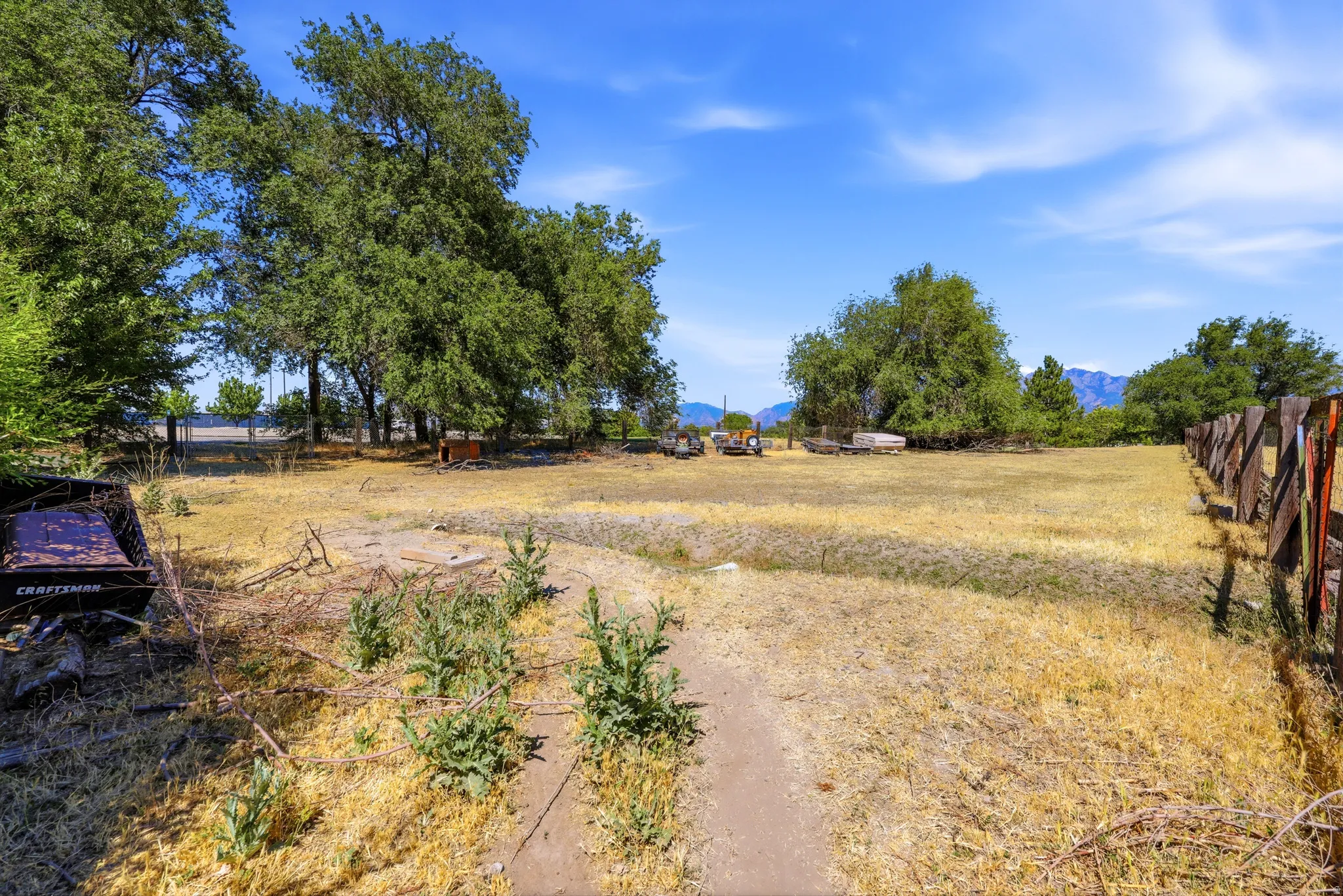 Expansive outdoor property with mature trees, natural terrain, and a rustic wooden fence line