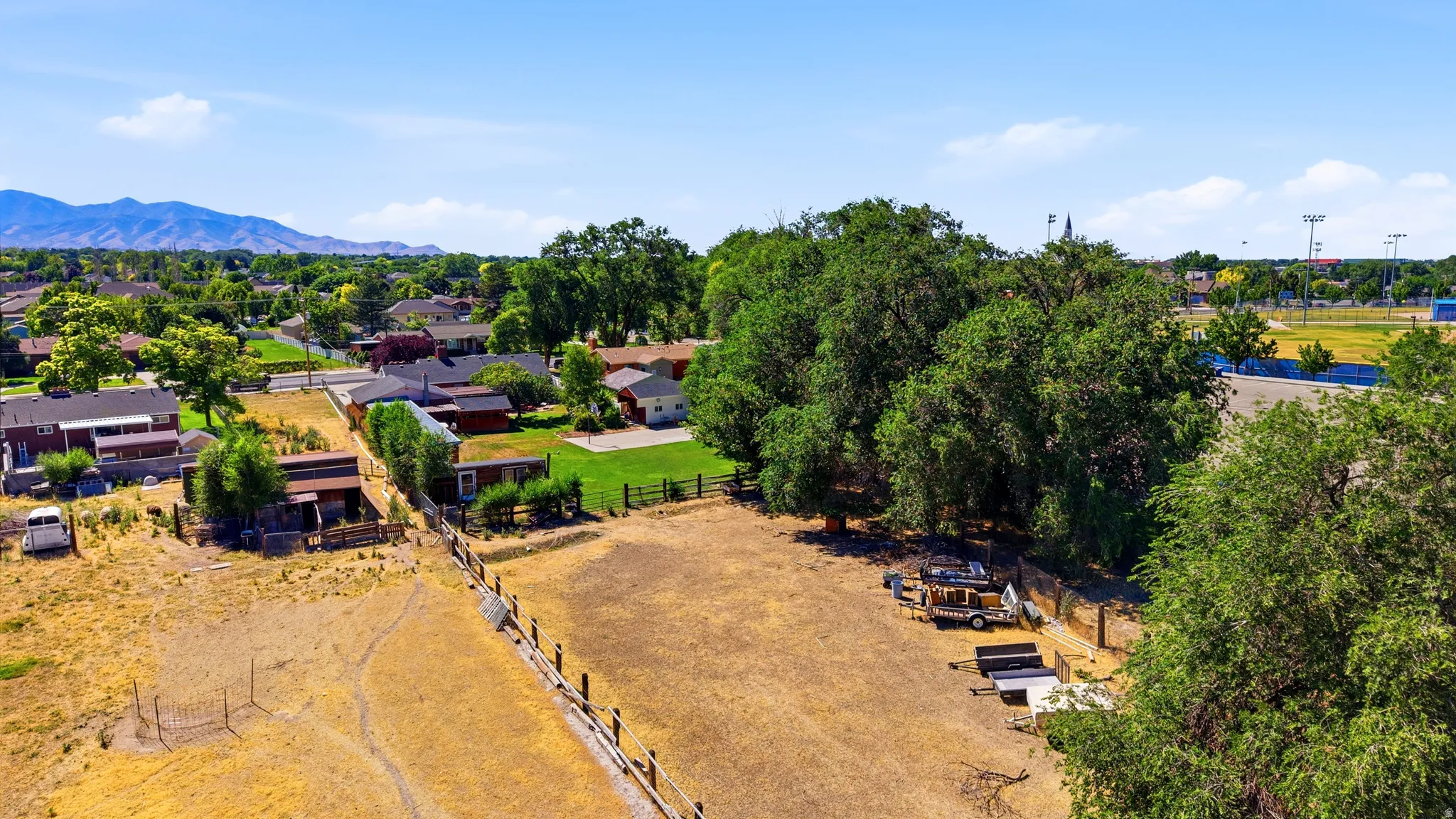 Expansive property featuring a large open field, mature trees, and fencing