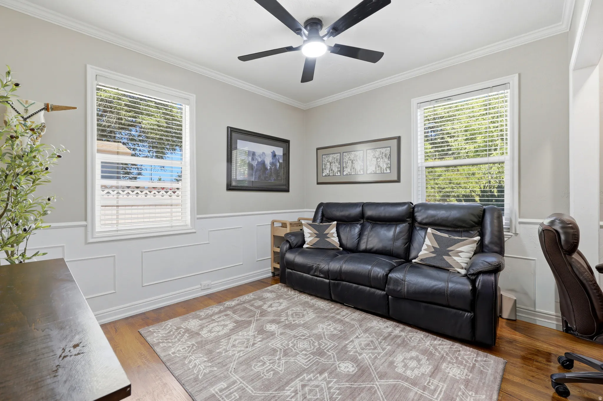 Room featuring light gray walls with wainscoting, white crown molding, and wood-finish flooring