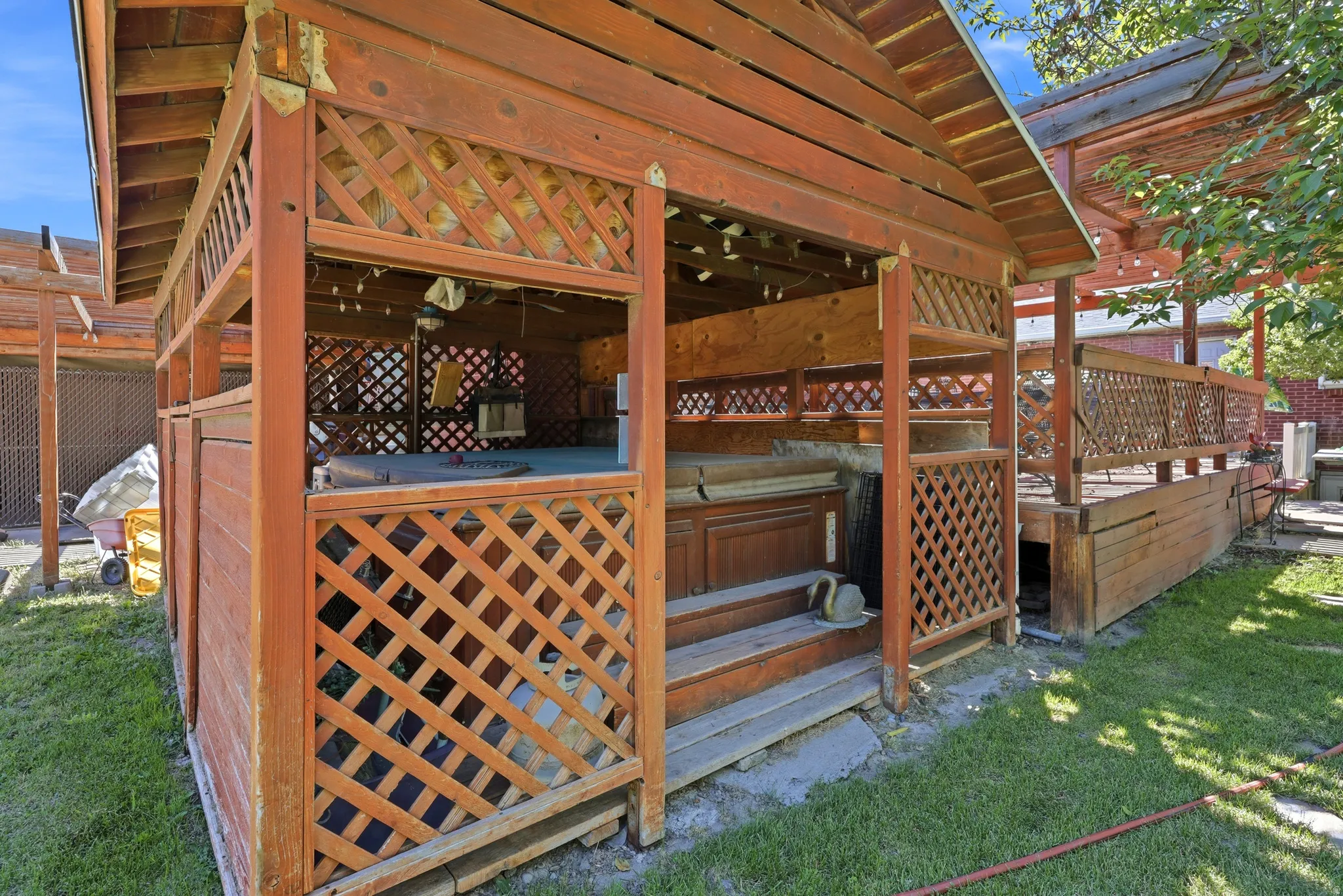Wood-paneled gazebo with lattice accents, featuring a built-in spa