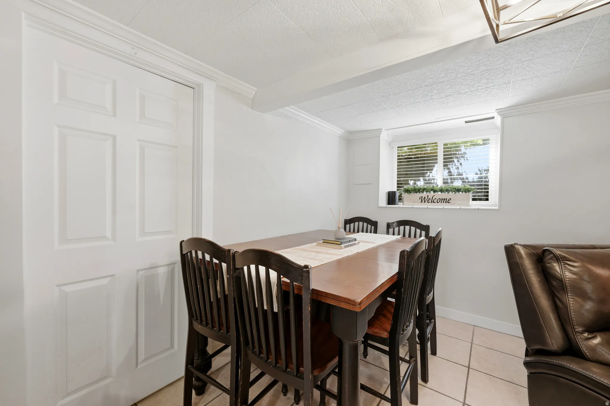 Dining area featuring a window with horizontal blinds, neutral wall paint, white trim, and light-colored tile flooring