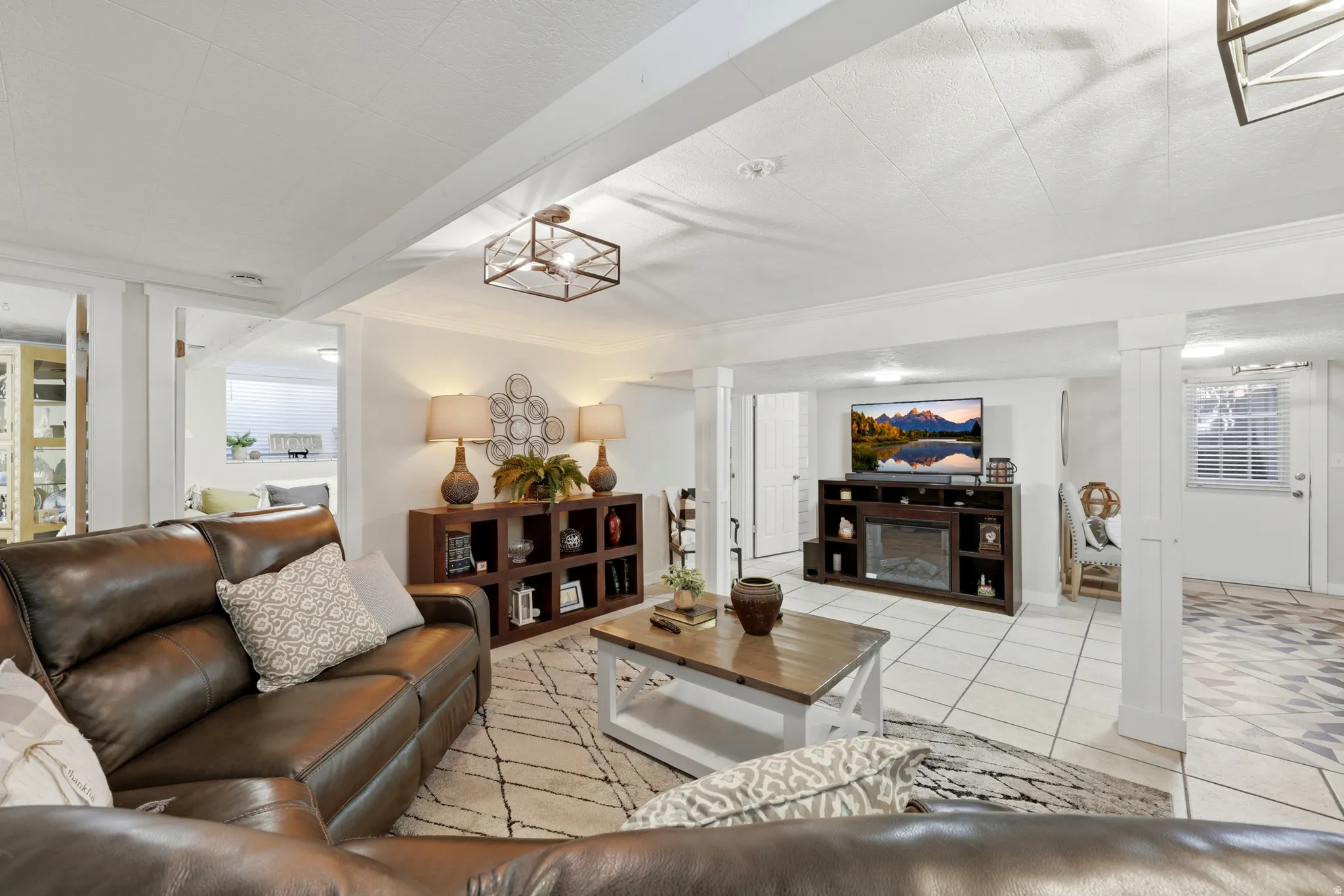 Open-concept living space featuring white tile flooring, recessed lighting, and exposed ceiling beams