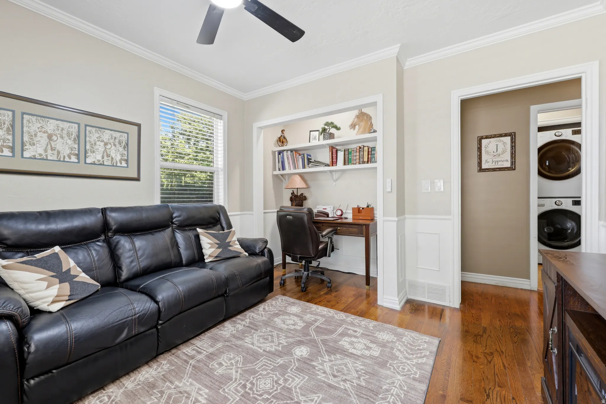 Room featuring wood-finish flooring, crown molding, and a ceiling fan