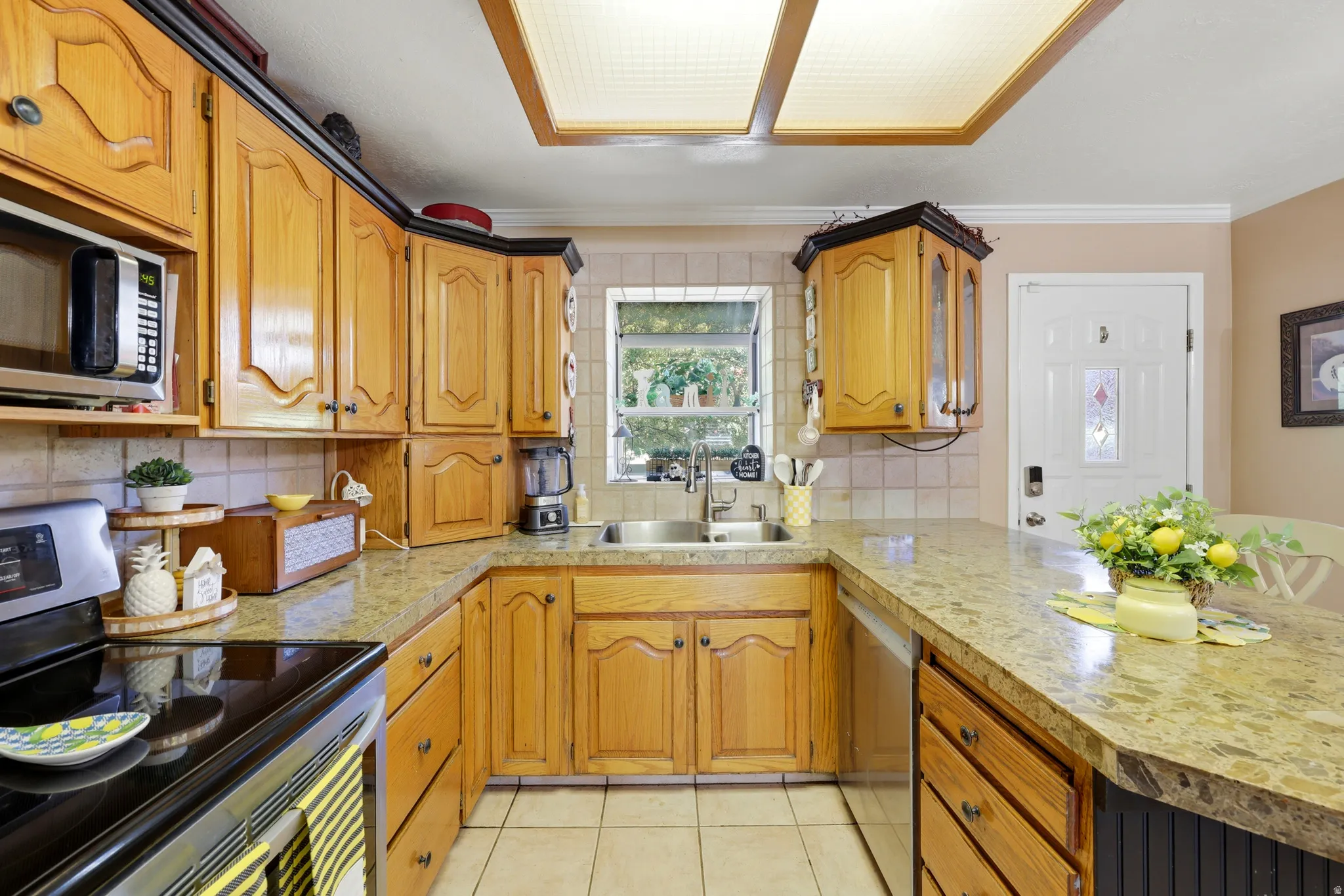 U-shaped kitchen featuring wood cabinetry, stone-finish countertops, and a tile backsplash