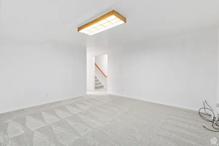 Bright room featuring light gray patterned carpet, white walls, and a wooden flush-mount ceiling light fixture