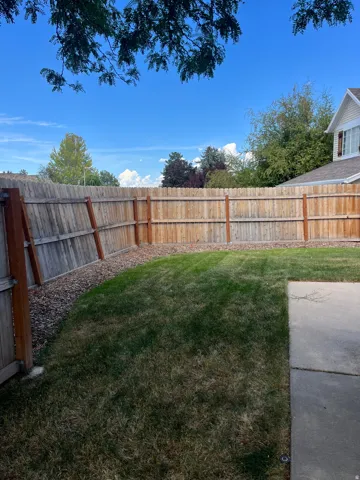 Private backyard featuring a wood privacy fence, expansive lawn, and concrete patio