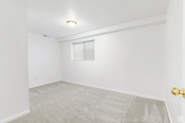 Room with light-colored carpeting, white walls, and a window with horizontal blinds