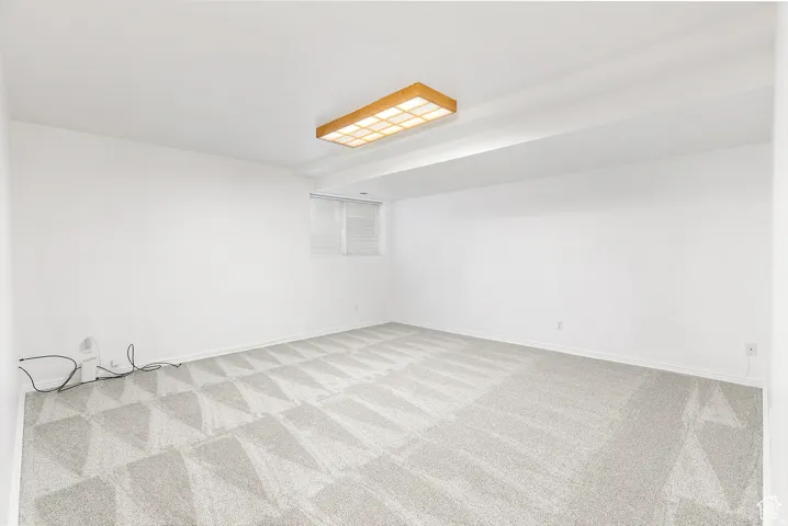 Spacious room featuring light gray patterned carpeting and white walls