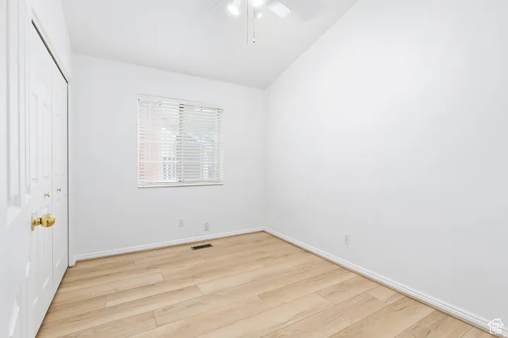 Room featuring wood-finish flooring, white baseboards, a white ceiling fan, and a window with horizontal blinds
