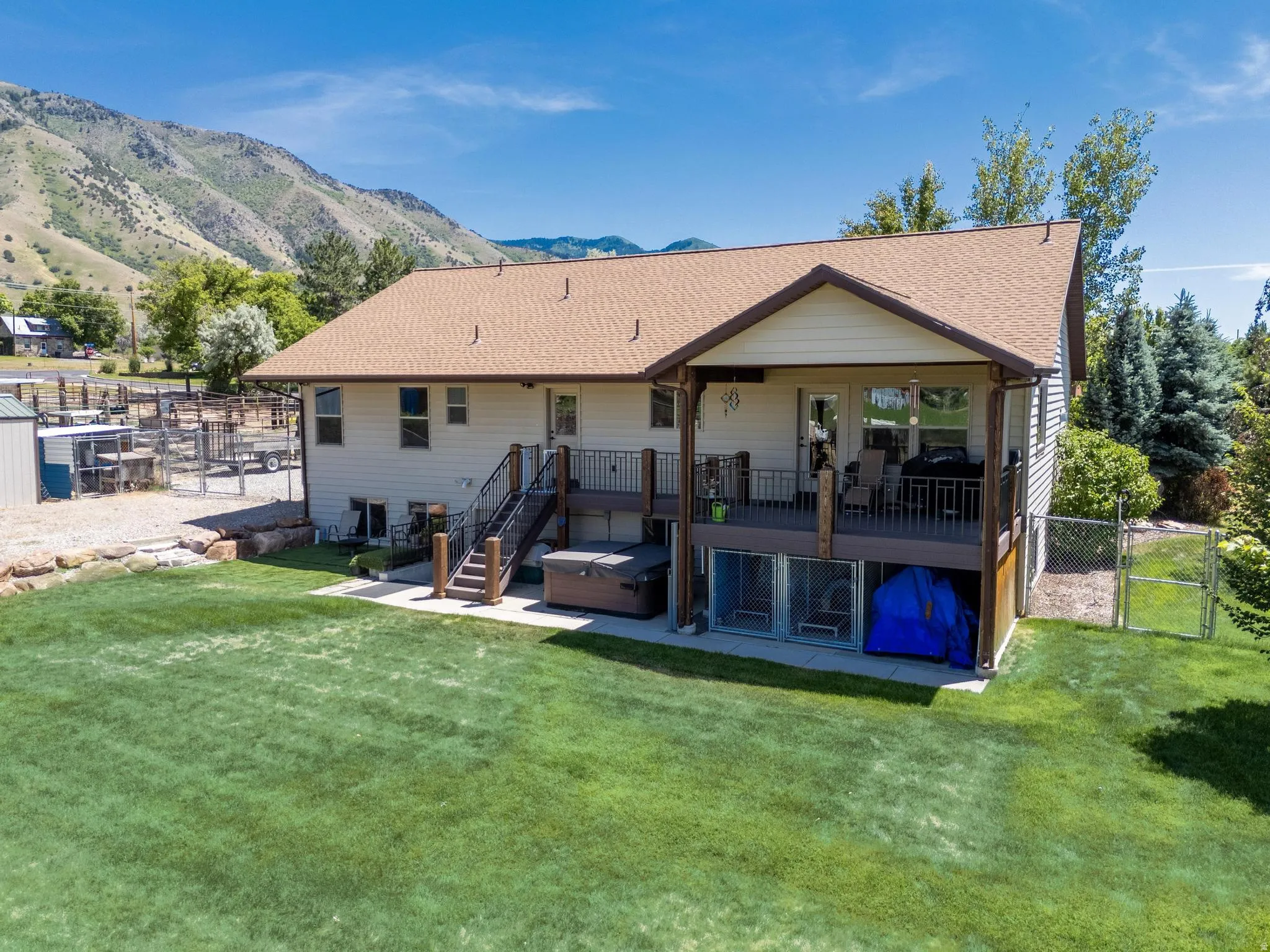 Rear exterior featuring a spacious elevated deck, lower-level patio, and a large grassy yard