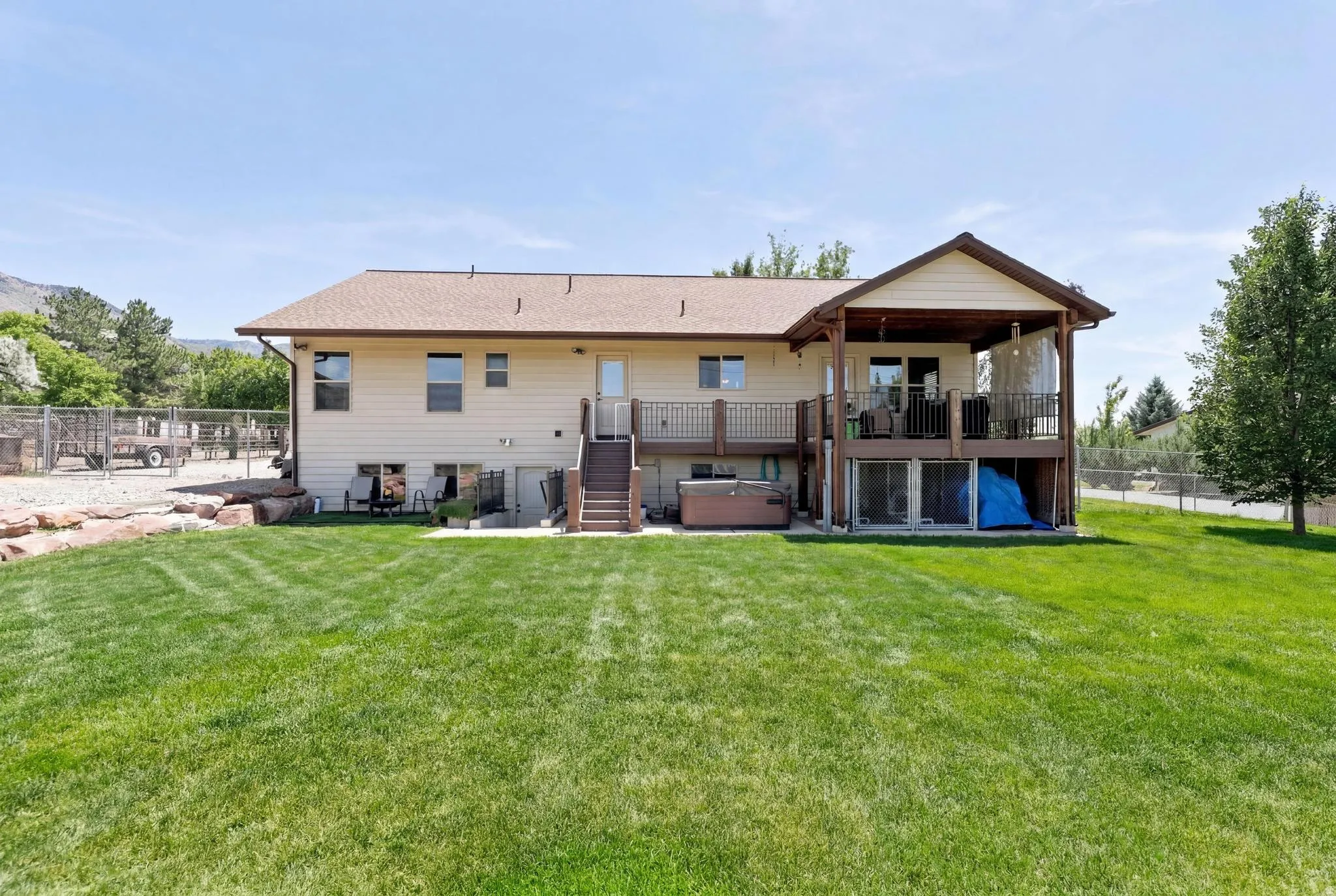 Expansive backyard featuring a manicured lawn, an upper-level covered deck, a lower-level concrete patio, and a walk-out basement