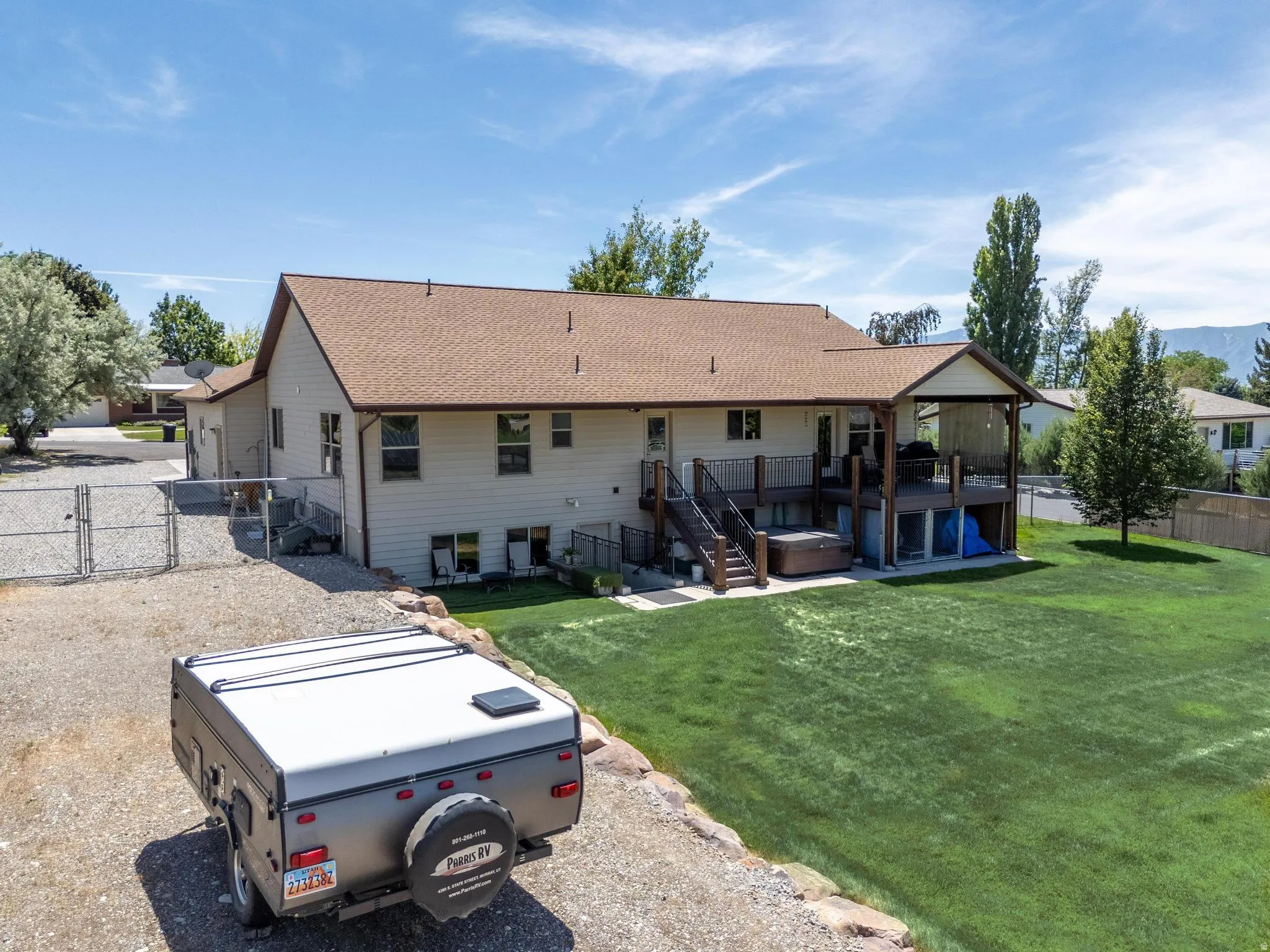 Expansive backyard featuring a manicured lawn, a multi-level deck with a covered portion, and an integrated hot tub