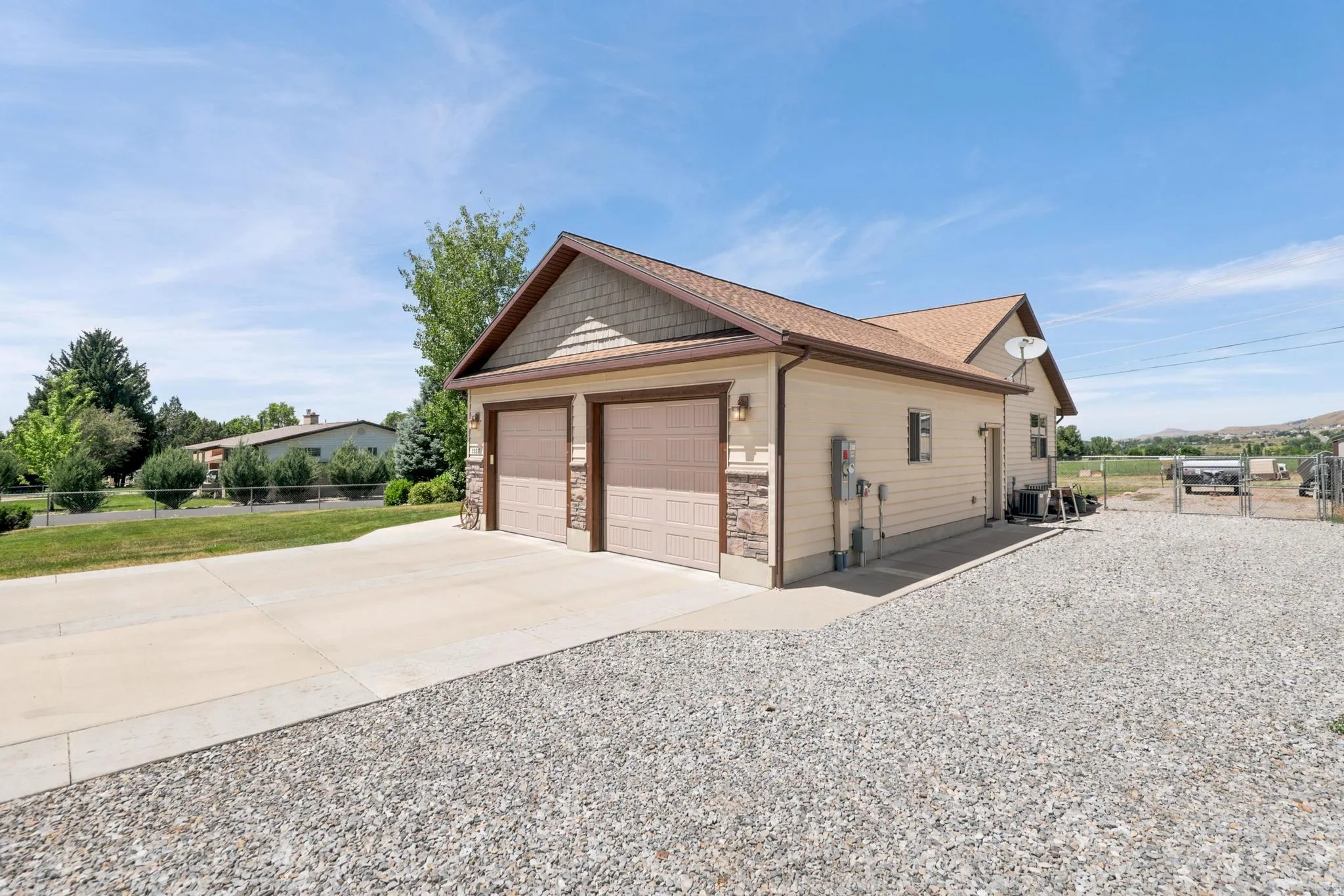 Two-car garage featuring a concrete driveway and an additional gravel parking area