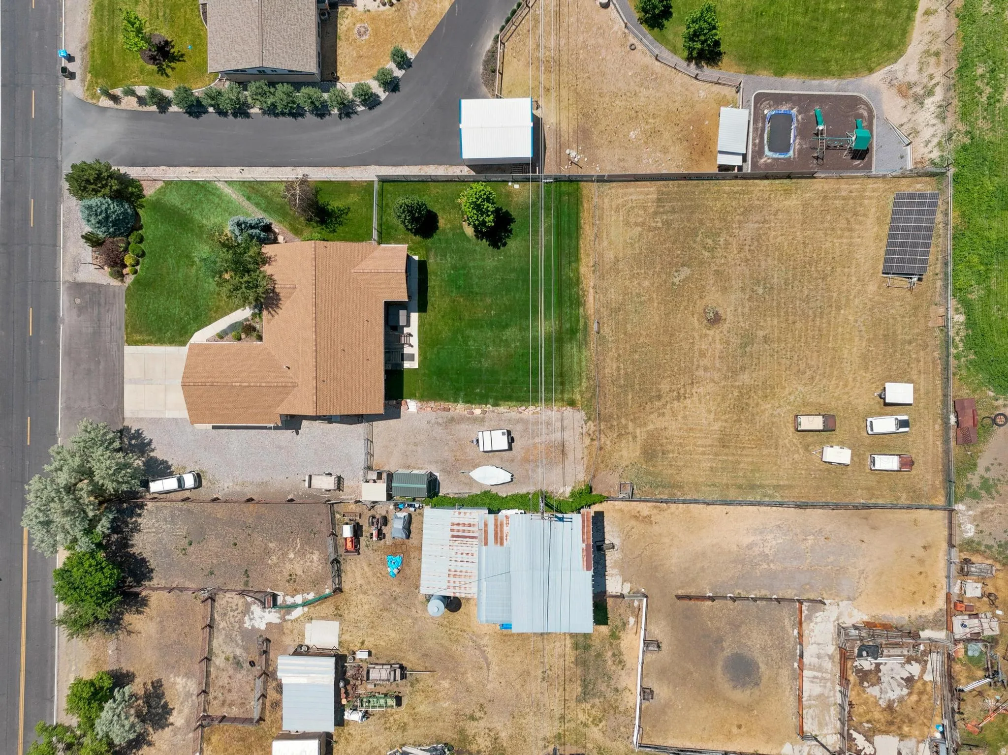 Expansive property featuring a residence with a brown shingle roof, a paved driveway, and established landscaping