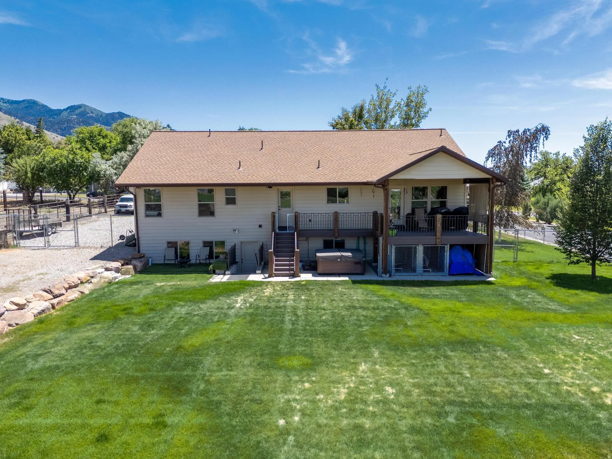 Expansive green lawn bordering a two-story residence with a multi-level deck