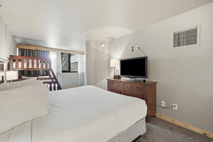 Carpeted bedroom with a built-in bunk bed, a window with curtains, and light gray walls