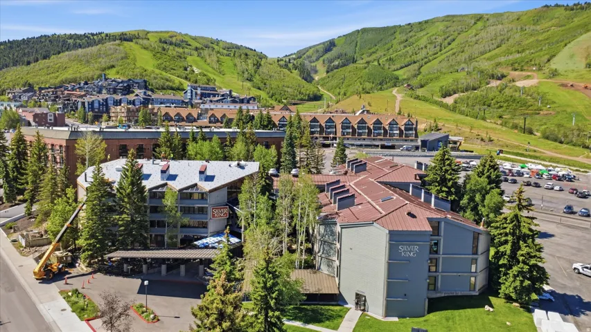 Expansive property featuring multiple buildings with gabled roofs, natural green landscaping, and surrounding mountainous terrain