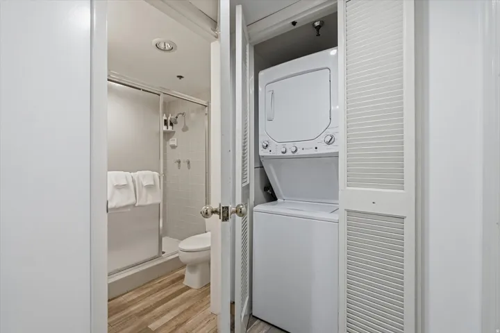 Compact laundry area featuring a stackable washer and dryer, situated within a louvered bi-fold closet