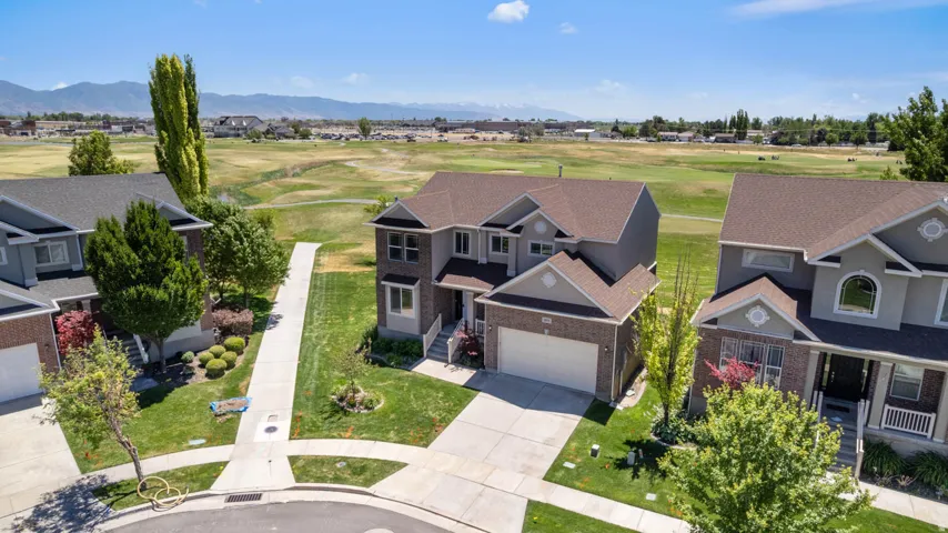 Two-story residence featuring a brick and siding exterior, front-facing garage, concrete driveway, and established landscaping