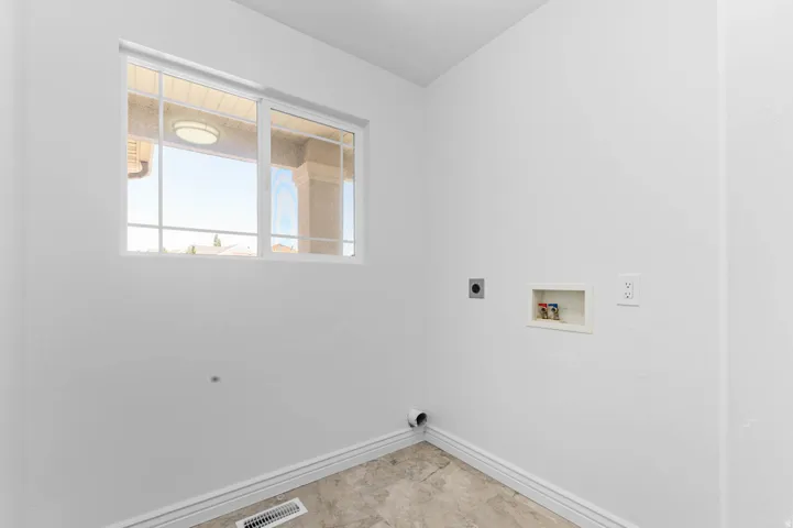 Laundry area with a grid-pattern window, neutral-toned flooring, white baseboards, and appliance hookups