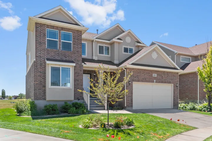 Brick and stucco exterior featuring multiple gables, an integrated garage, and a covered entry