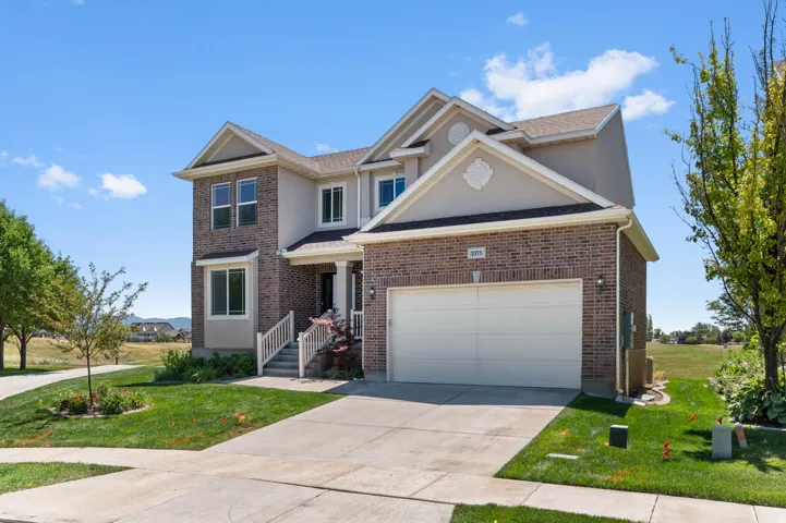 Two-story residence featuring a brick and stucco exterior, an attached two-car garage, and a concrete driveway