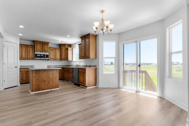 Open-concept kitchen and dining area featuring wood-finish flooring, recessed lighting, and a chandelier