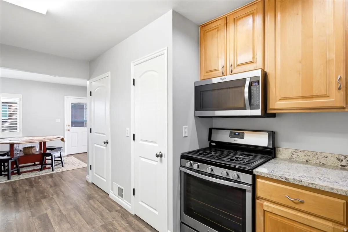 Kitchen featuring stainless steel oven with gas cooktop, stainless steel microwave, beautiful cabinetry, and granite countertops