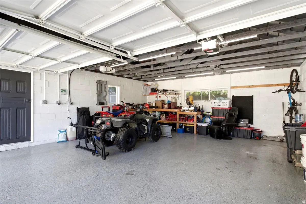 Spacious garage featuring an epoxy-coated concrete floor, white block walls, and overhead fluorescent lighting
