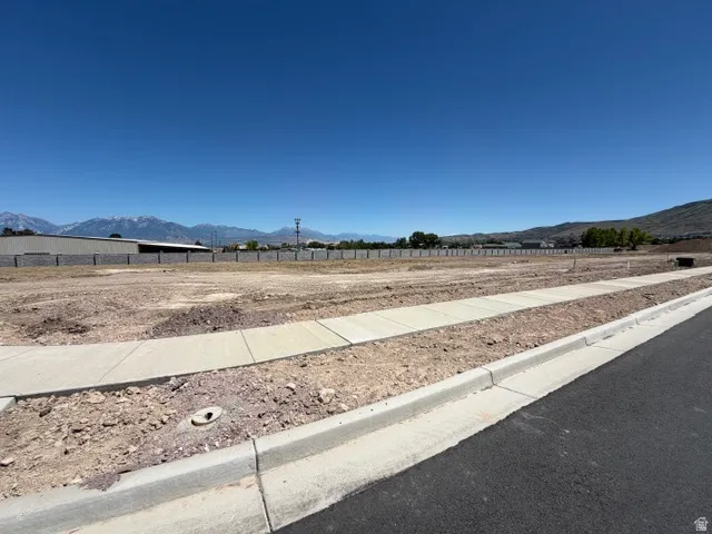 Cleared building lot featuring newly installed curbs, sidewalks, and street paving