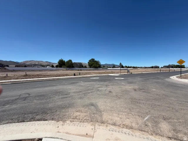 Expansive undeveloped land parcel featuring existing paved roads, curb and gutter infrastructure, and distant mountain scenery