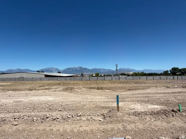 Expansive undeveloped land featuring a stone-look perimeter wall, distant mountain range, and clear blue sky