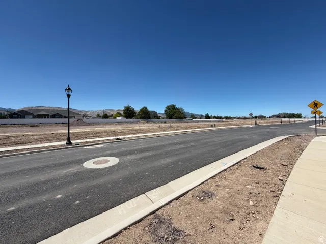Newly constructed road featuring paved asphalt, concrete curbs, and a dedicated sidewalk