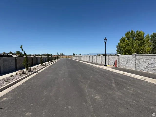 Entrance to Subdivision. Paved roadway bordered by stone veneer privacy walls featuring capped pillars and integrated street lighting
