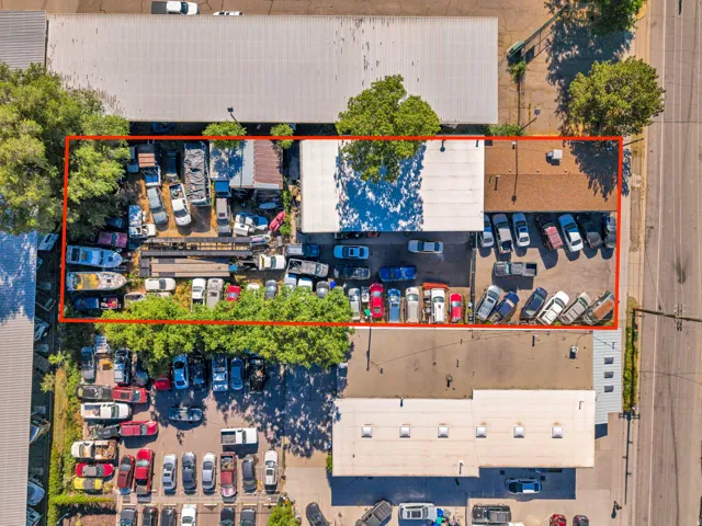 Aerial view showcasing a commercial property featuring a combination of paved parking areas and an expansive open storage lot