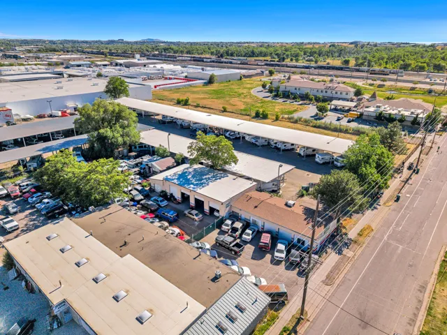 Expansive commercial property featuring multiple buildings, generous paved parking areas, covered parking structures, and direct street frontage