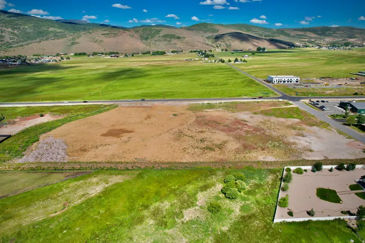 Expansive land parcel featuring a road frontage, a varied topography with both cleared and vegetated sections, and distant mountainous terrain
