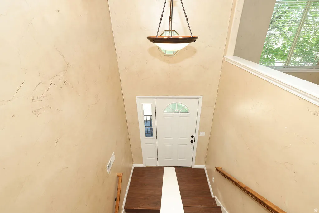 Entryway featuring a high vaulted ceiling, wood-finish flooring, and a decorative pendant light fixture